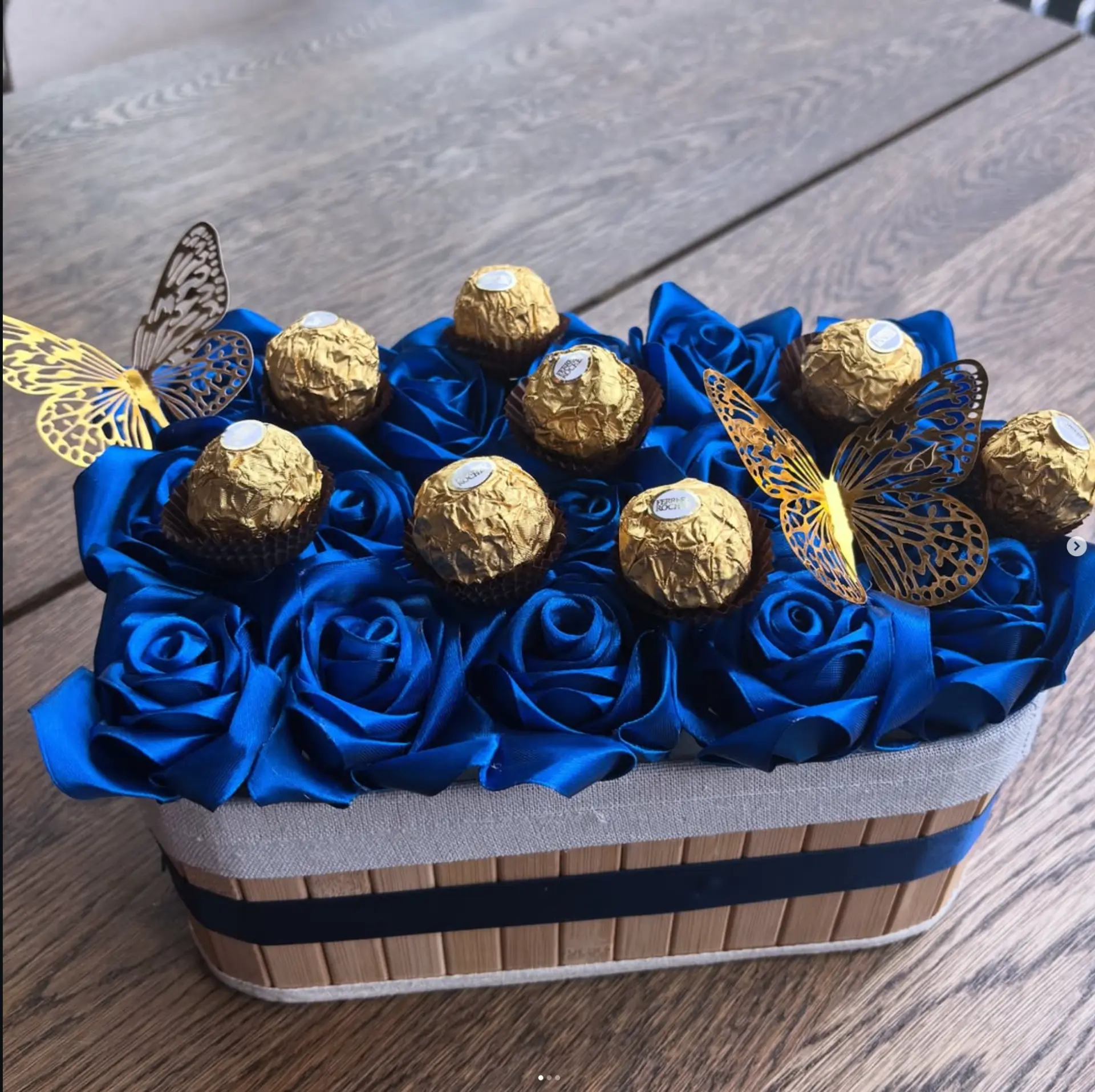 Handmade royal blue satin roses arranged in a wooden box with Ferrero Rocher chocolates and gold butterflies
