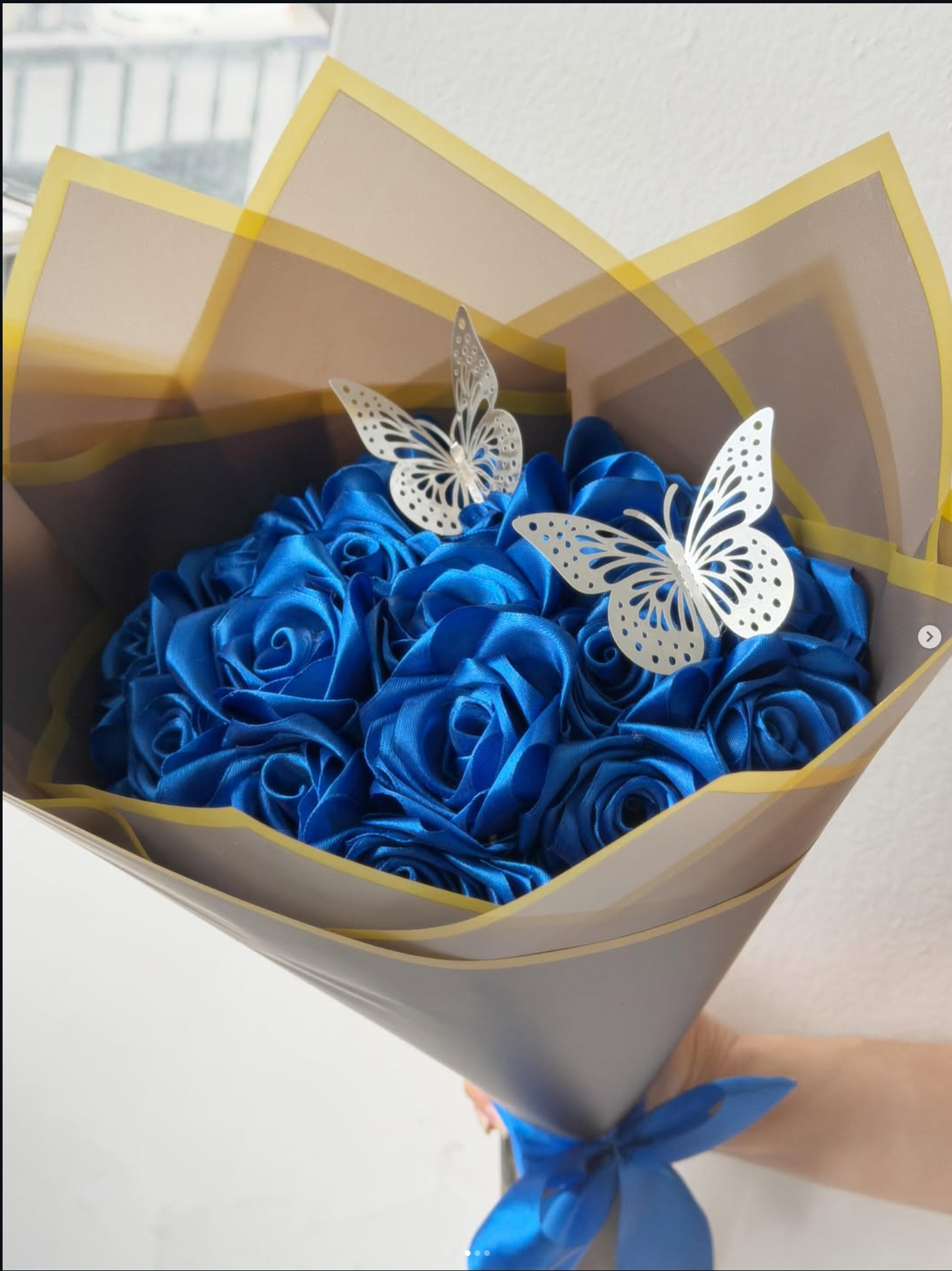 Bouquet of royal blue eternal satin roses wrapped in grey and gold paper with white butterflies